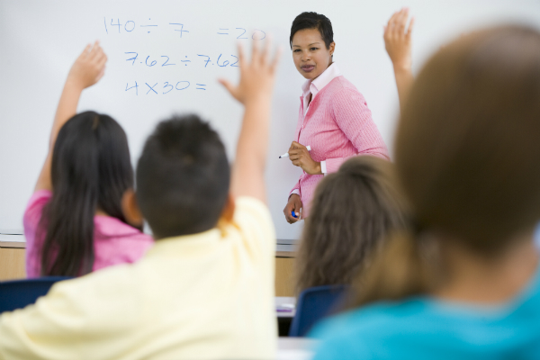 A teacher stands at her whiteboard using one of the depth of knowledge levels to teach.