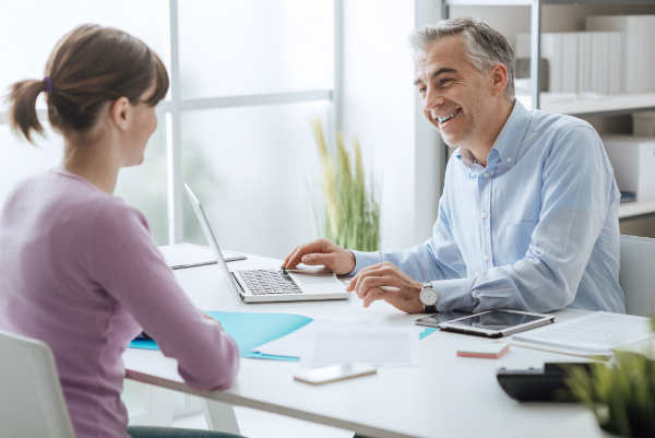 A principal sits at his desk, setting SMART goals with this teachers, which is an important instructional leadership strategy.