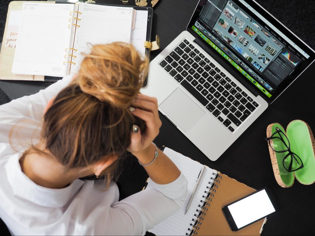 Burned out teacher sitting at desk with her head in her hands.
