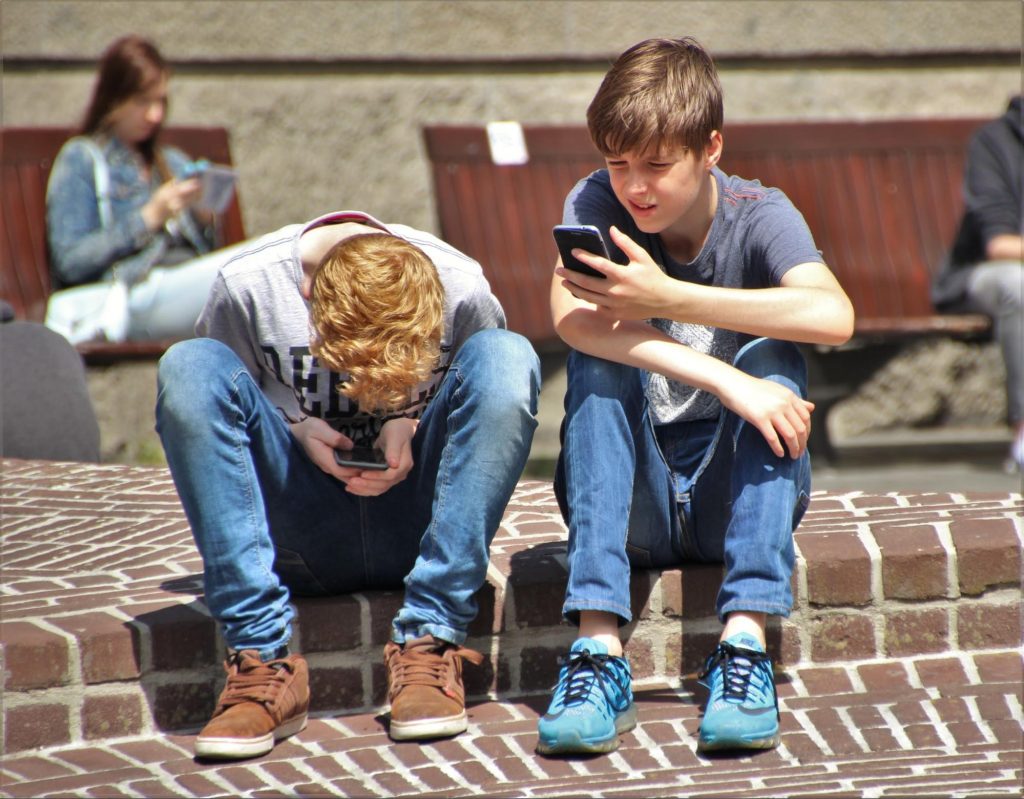 two teenagers and technology sitting outside